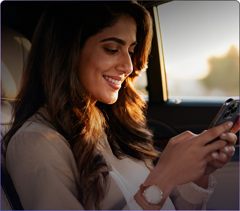 Woman smiling while using her phone in a car